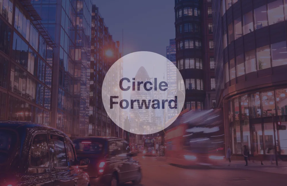 London street scene with commercial office buildings, moving traffic and a circular graphic overlay displaying the text “Circle Forward”.