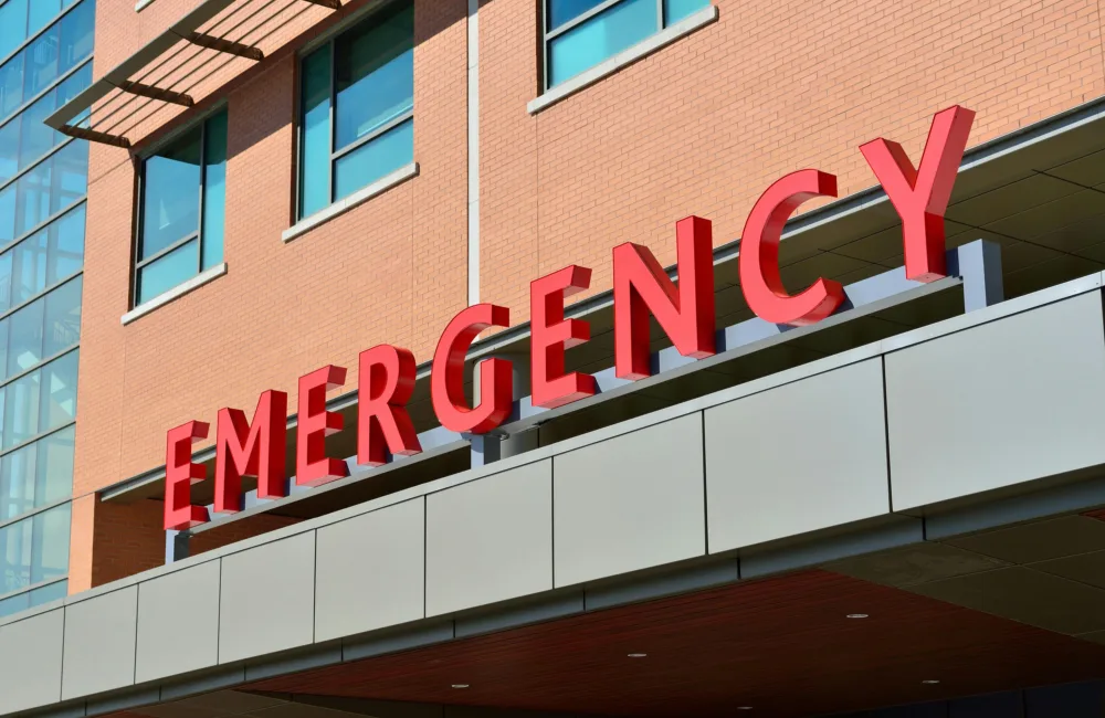 Red emergency lettering on front of a brick and glazed building