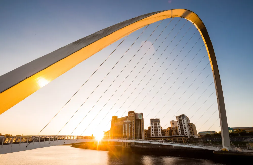 Sun reflecting on the bridge over the river Tyne in Newcastle with the Baltic Flour Mills in the distance