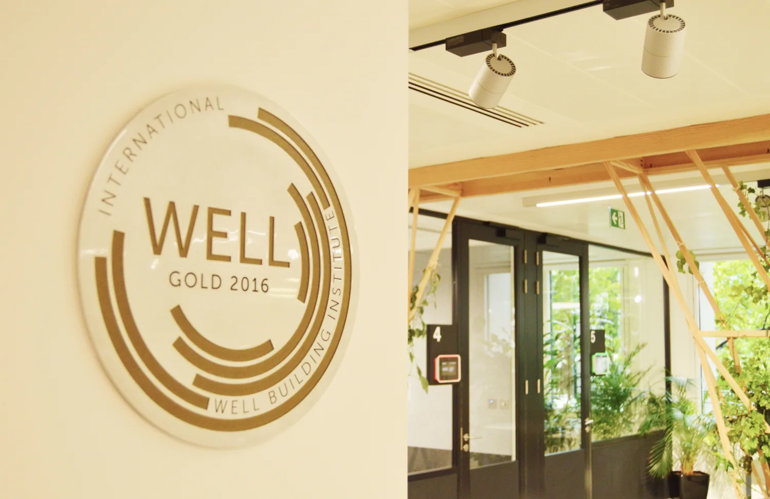 WELL Gold 2016 plaque mounted beside an interior with glazed doors, timber framing and planting.