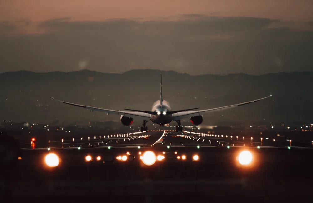 Plane landing on an illuminated runway at dusk