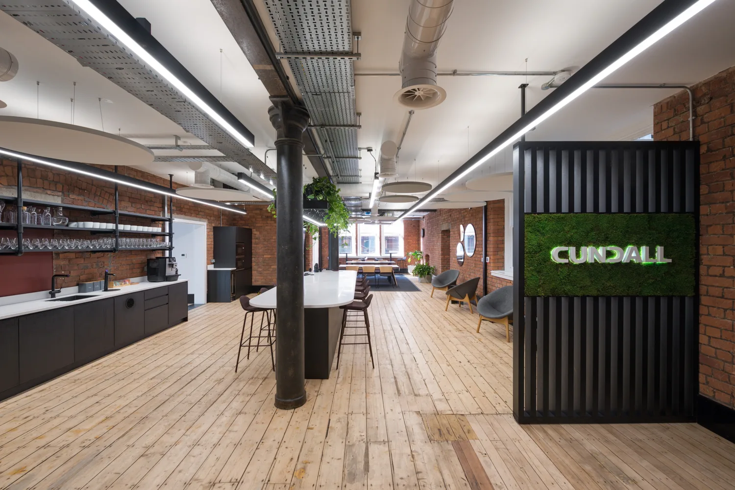 Wooden floor, exposed brick walls black wooden slat wall with green panel with a white cundall logo