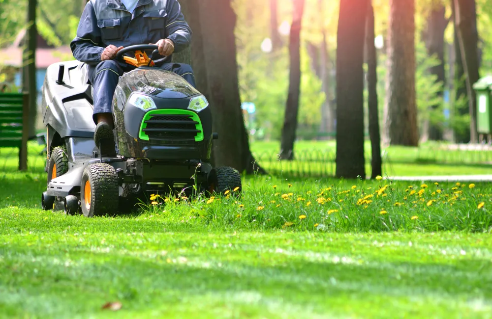 Man sitting on ride on lawn mower cutting grass