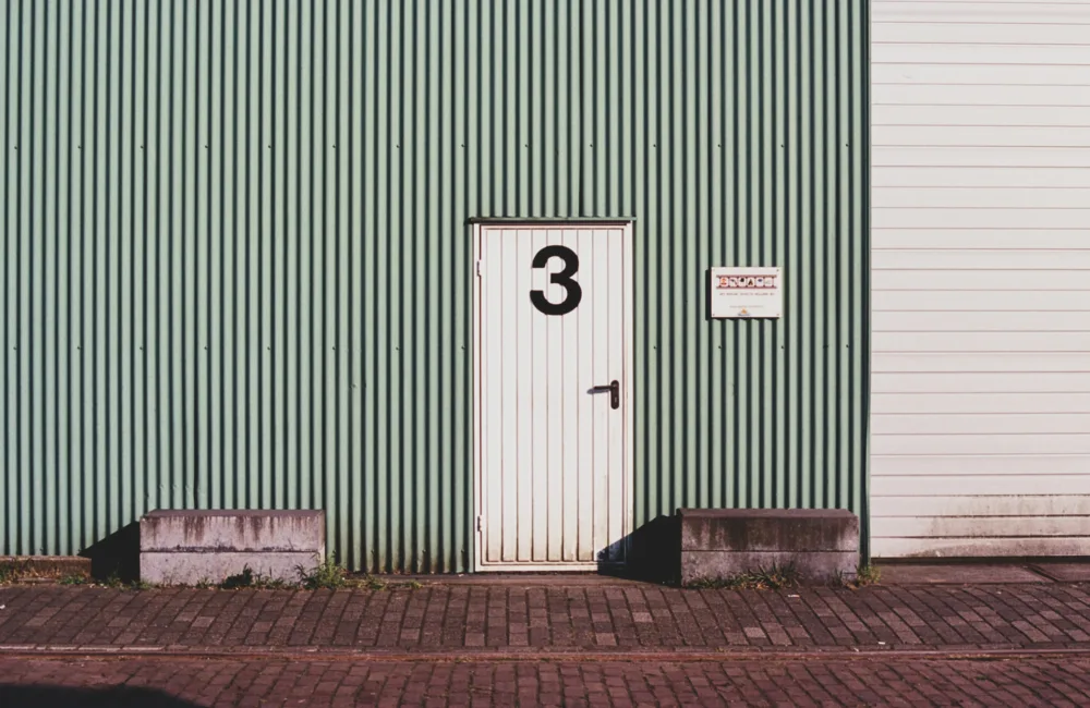 A white door of a warehouse with the number three printed on it.
