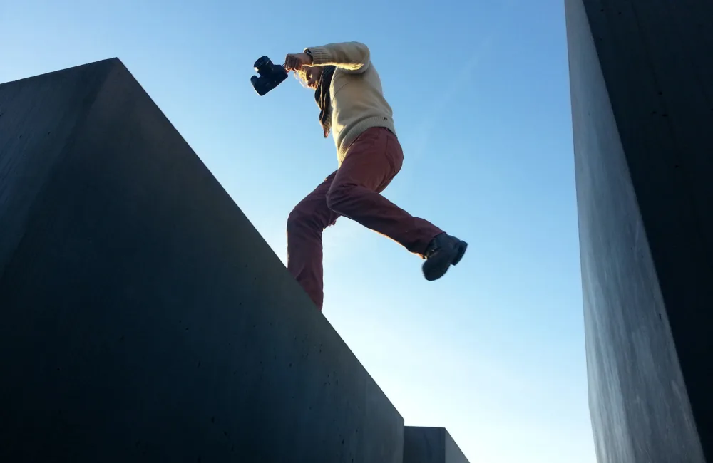 Man jumping between concrete structures, against a blue sky background