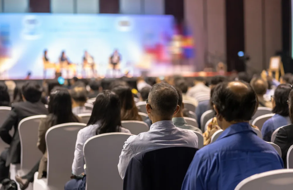 An audience listening to a panel of speakers in a conference