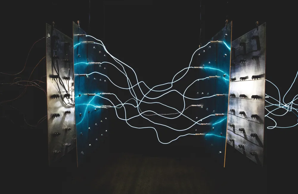 Wires between 2 electricity panels glowing against a dark back ground