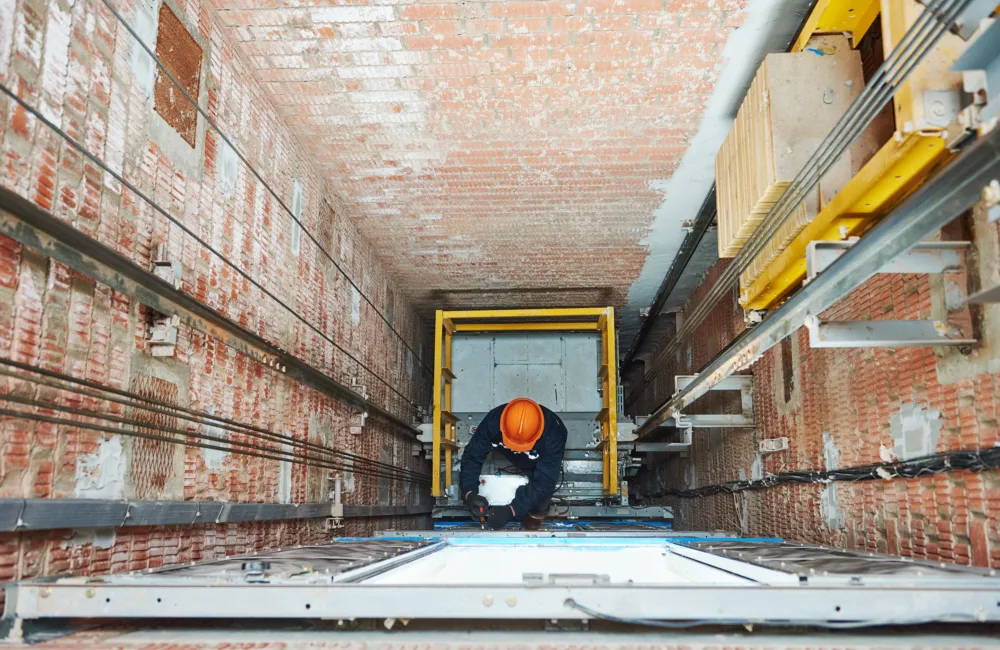 Man at the bottom of lift shaft working on cables