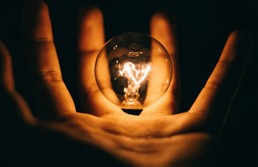 Hand holding edison light bulb with black background