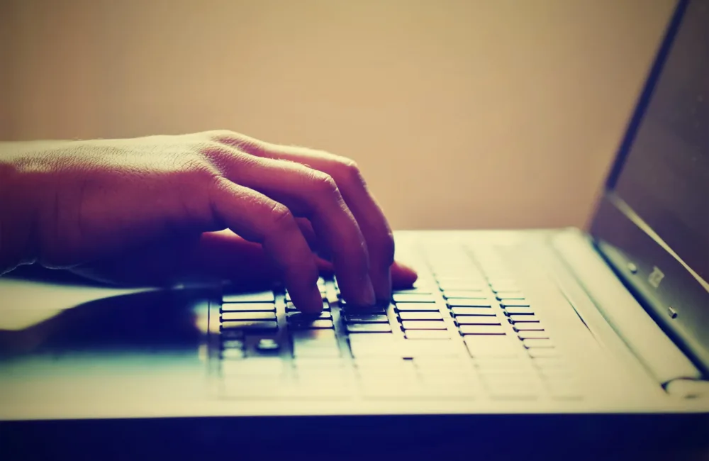 Close up of persons hand typing on laptop