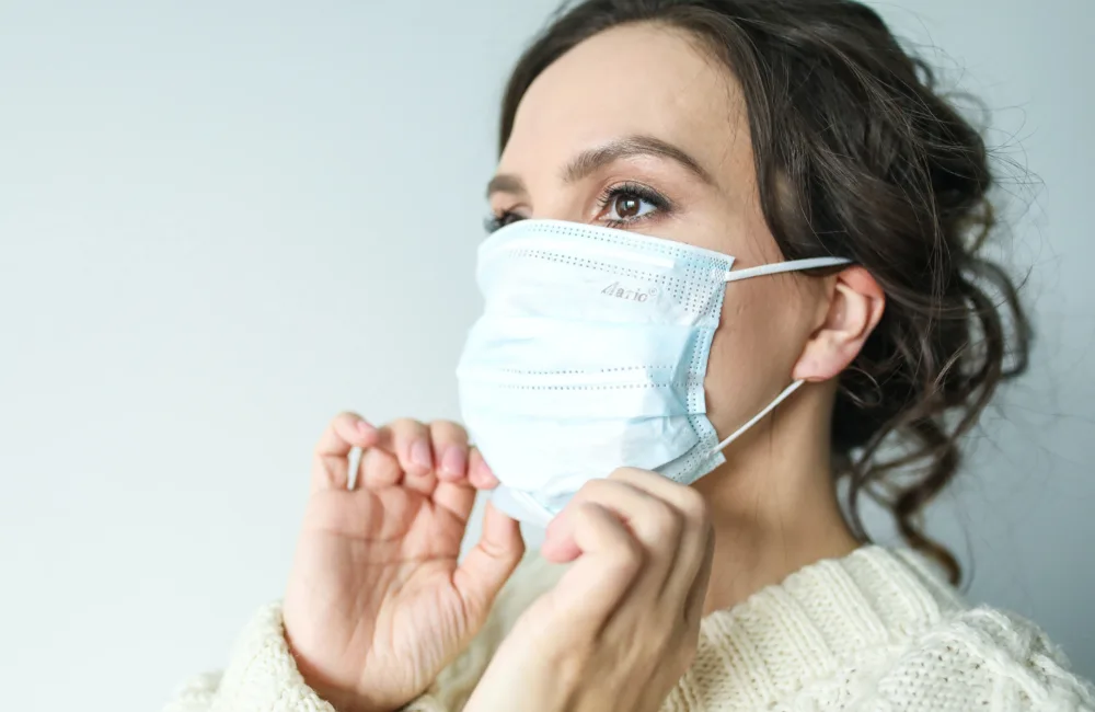 Side profile, close-up of a woman putting on a face mask.