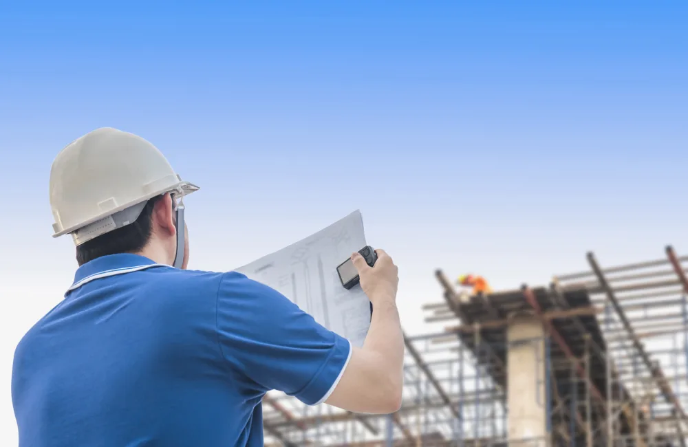 Builder looking up at a construction site and plan.