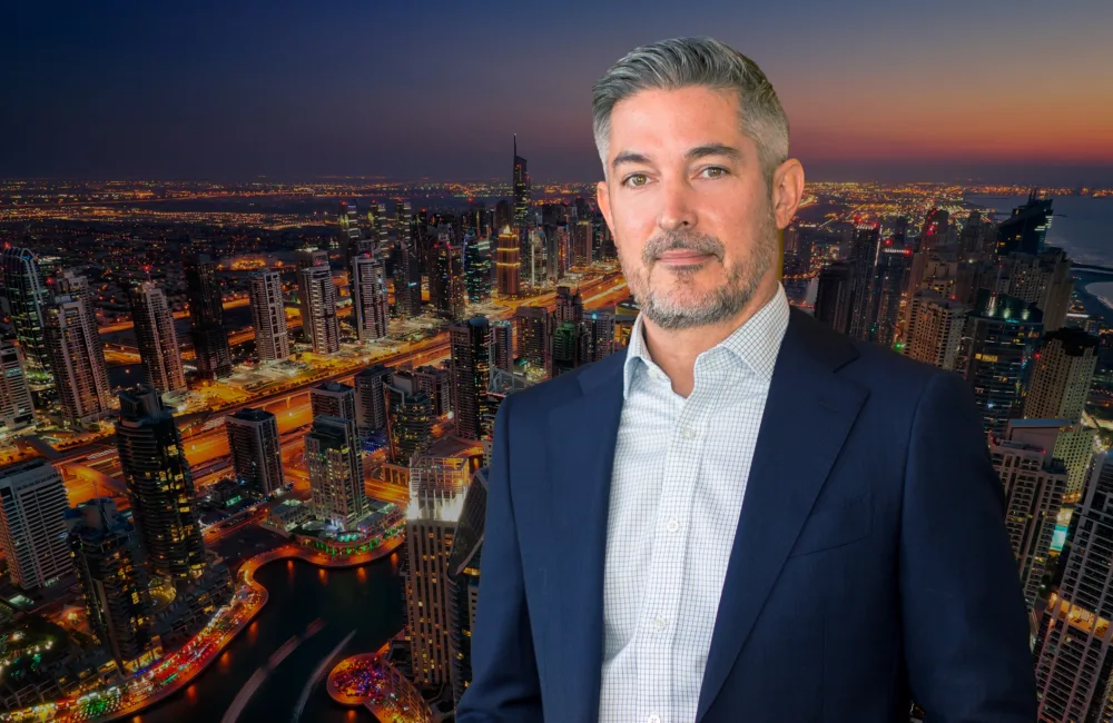 Portrait image of Scott cropped with a view of the Dubai skyline in the background.
