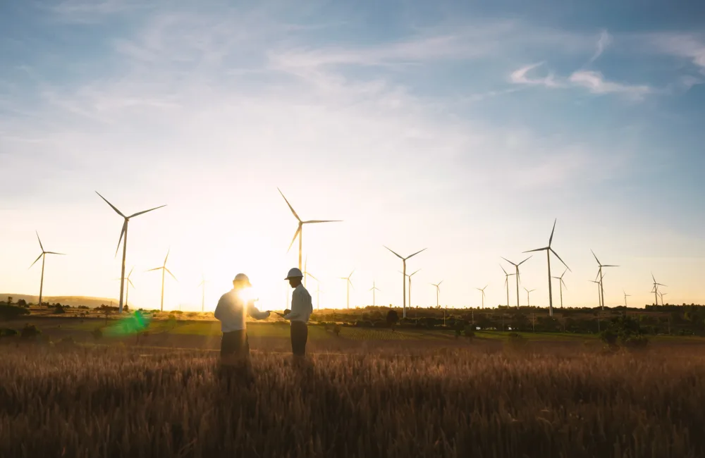 Two engineers are standing in front of wind turbines.