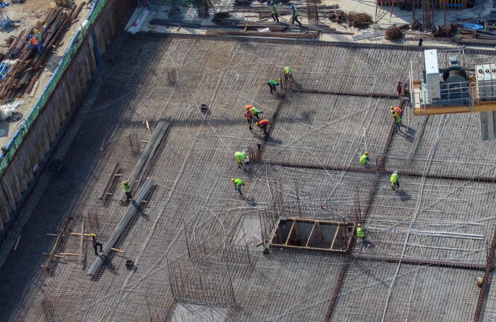 Workers are working at a construction site building up the foundation of the structure.