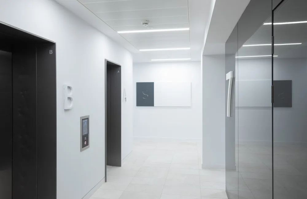 White office corridor with black shiny lift doors