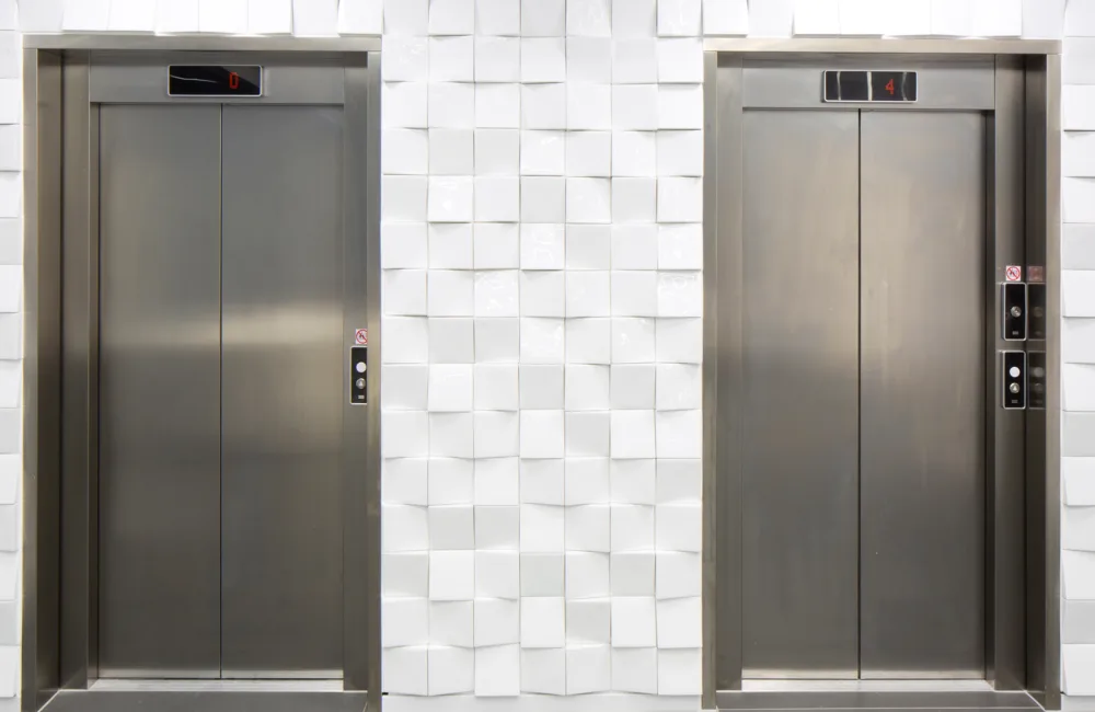 Two lift doors side by side against a white textured wall