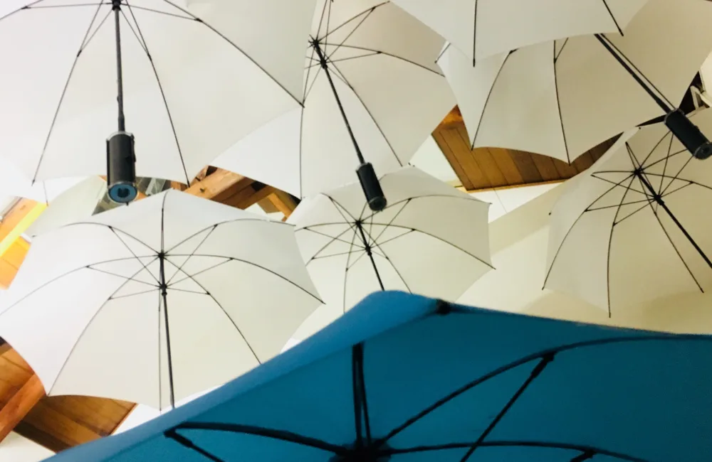 Underside view of an art installation of multiple white umbrellas