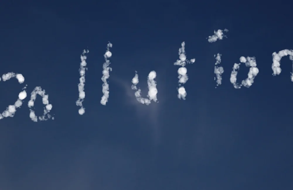 The word 'pollution' formed with clouds against a blue sky