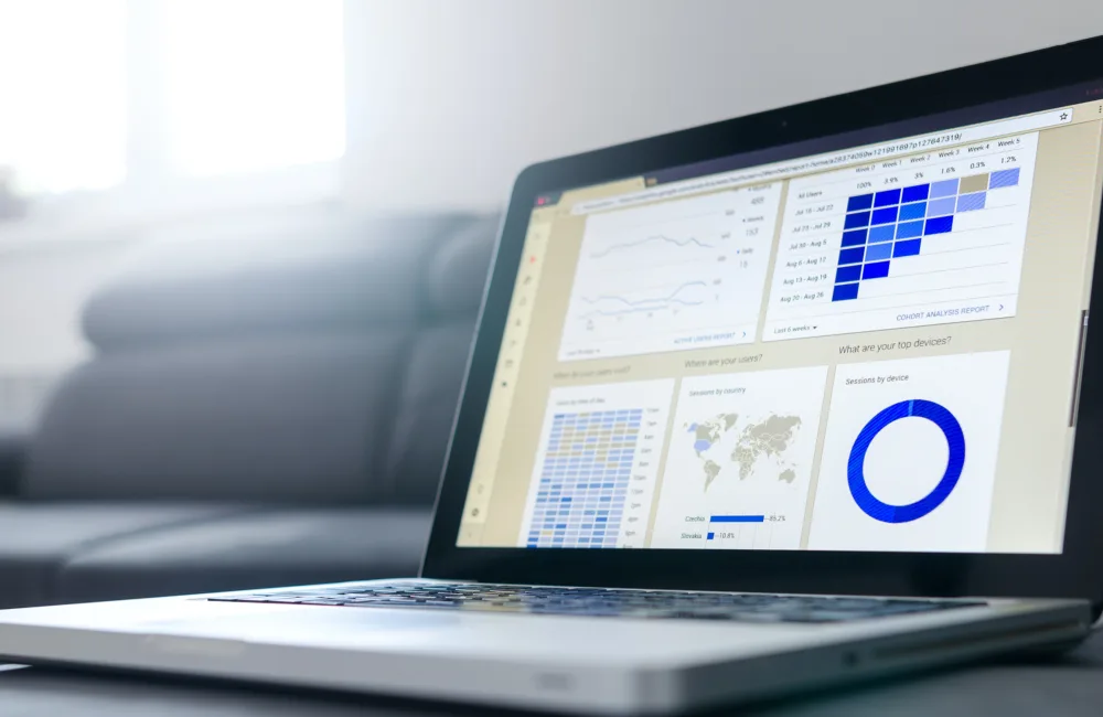 Laptop screen showing data and analytic tools, background is what looks like a living room