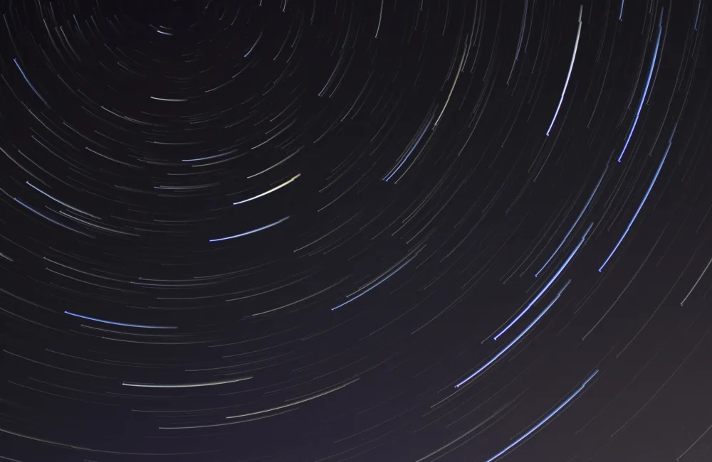 Long exposure photo of a dark night sky with the circular movement of white stars