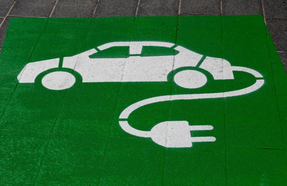 Painted flooring of a car parking space indicating a white electric vehicle on a green background