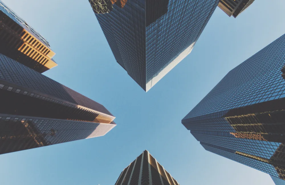 Looking up at tall glass skyscrapers against a blue sky
