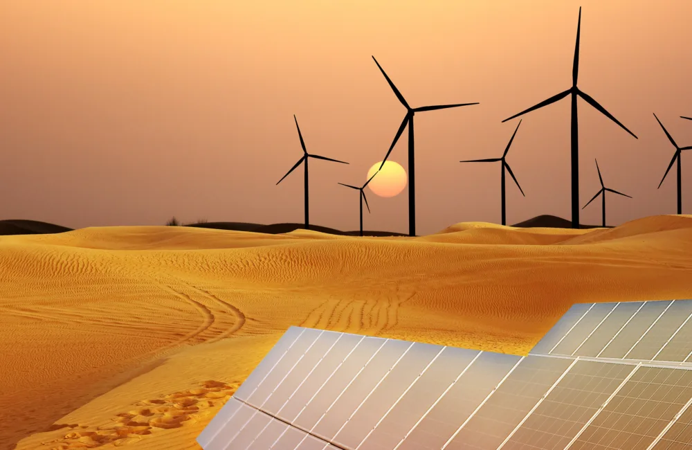 A desert image with solar panels in the foreground and silhouettes of wind turbines