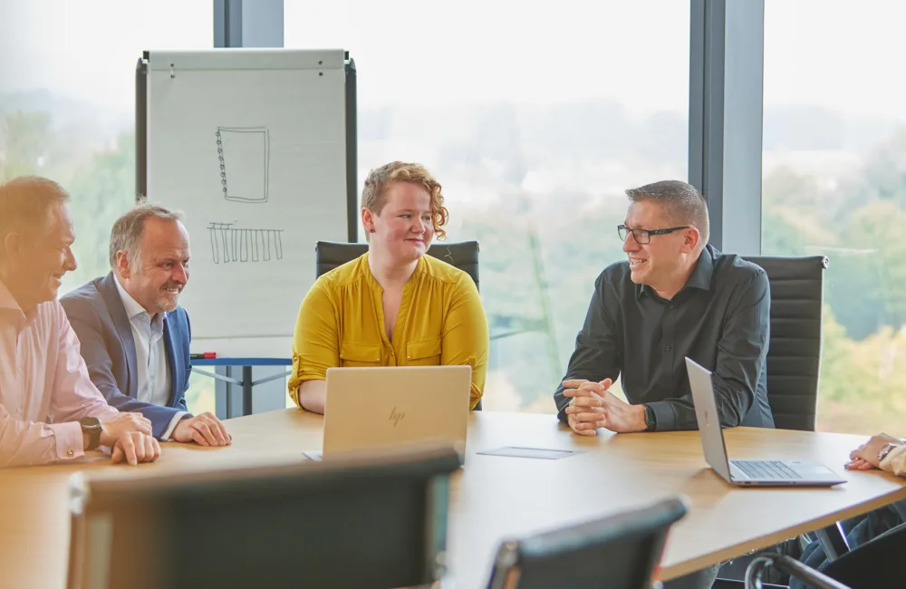 People at a discussion around the table with glass backdrop and flip chart