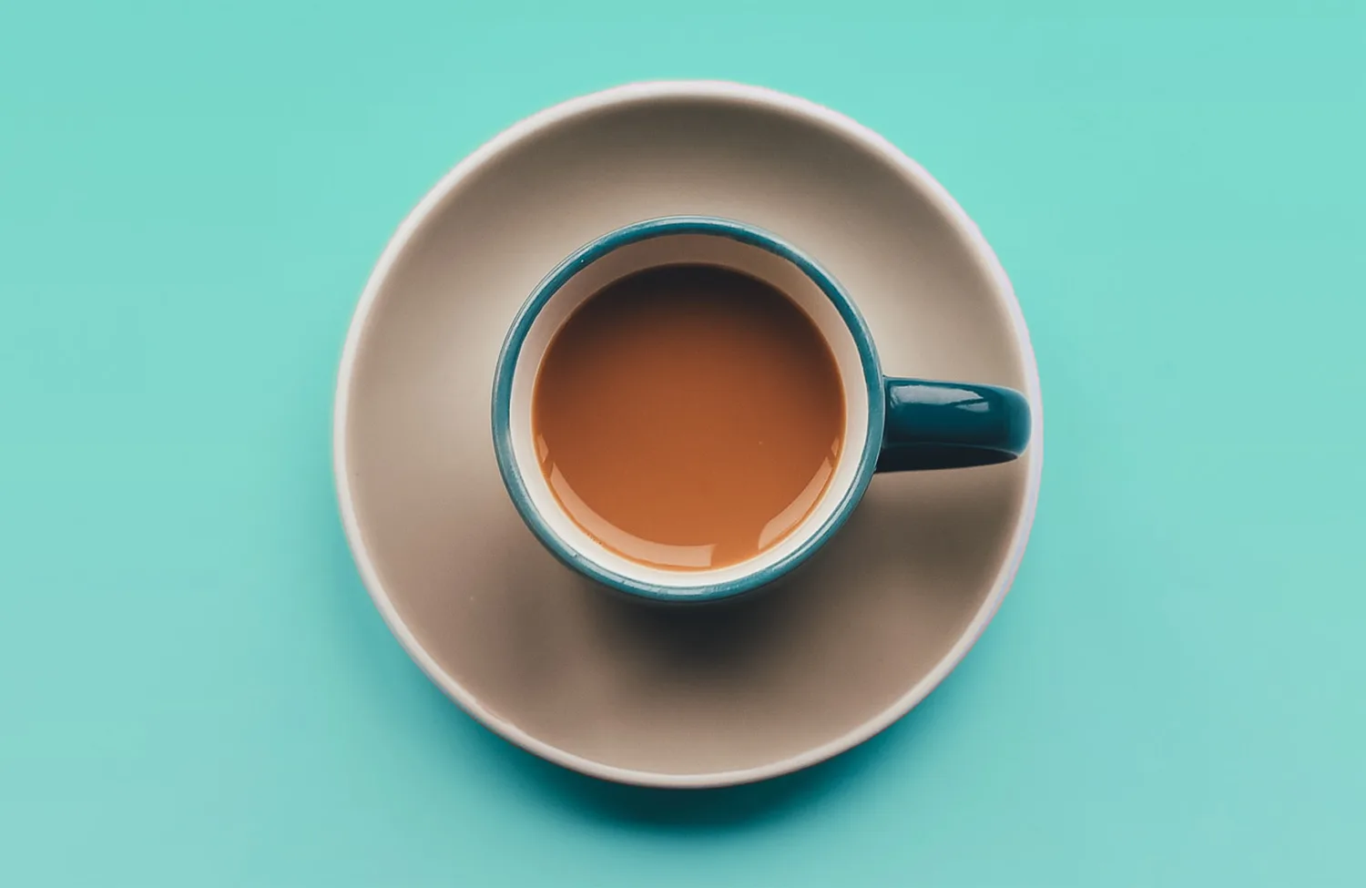 Sage green background with coffee cup and saucer on it