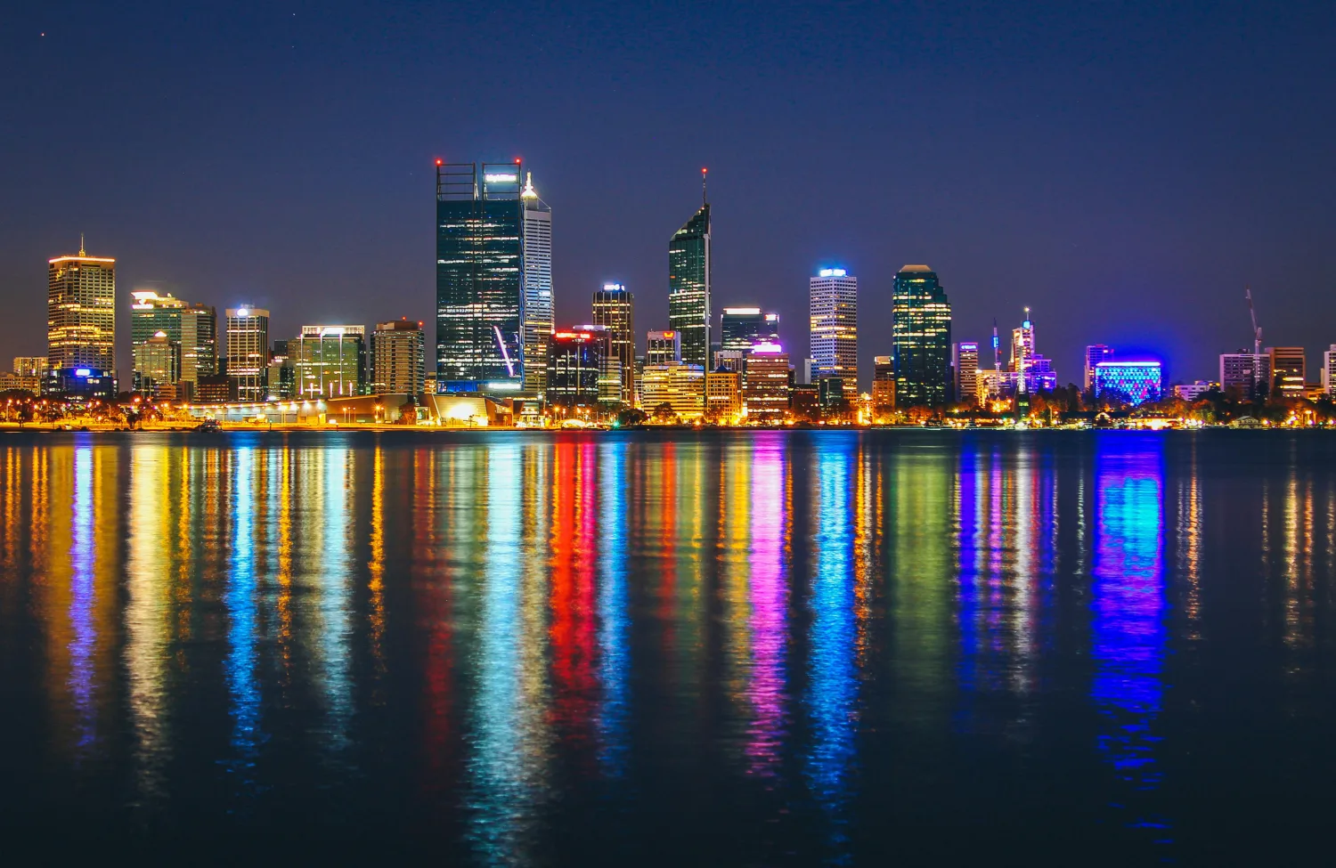 Perth skyline at night with the colourful building lights reflecting in the water