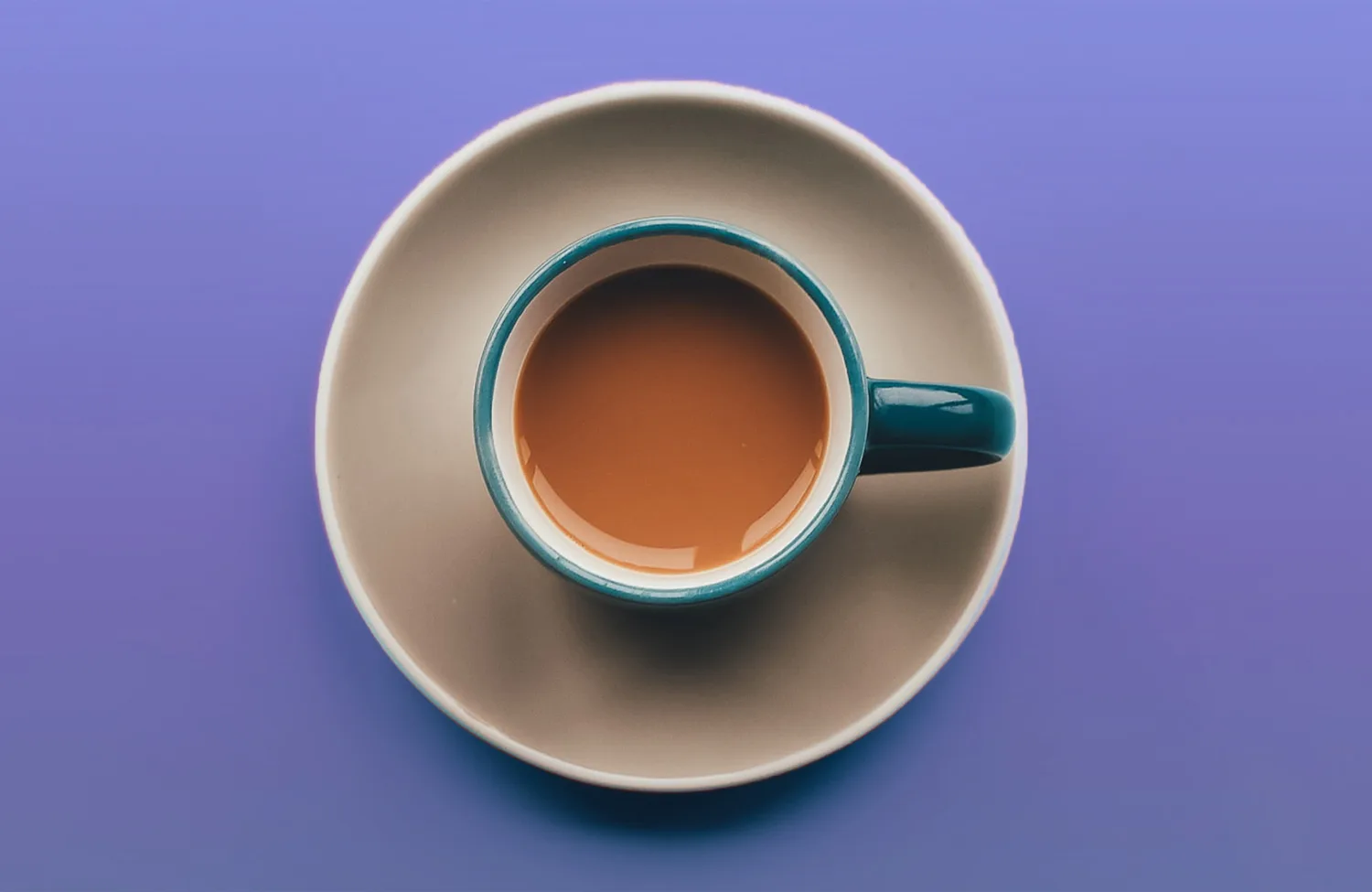 Aerial view of a tea cup and saucer on a purple background