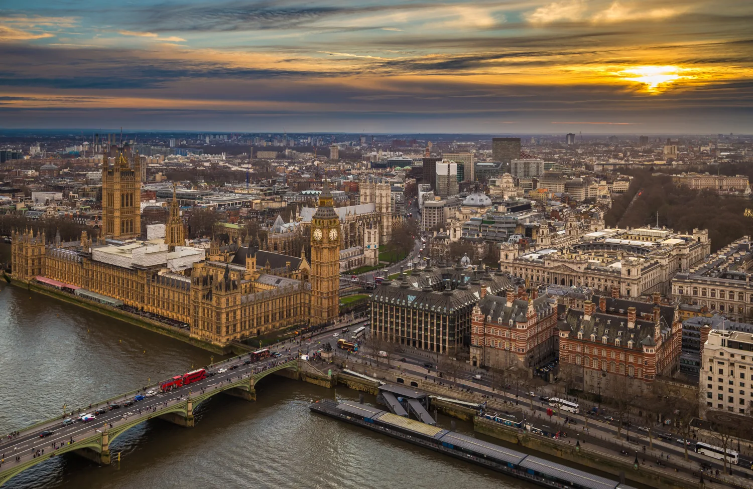 Aerial view of Westminster with the Houses of Parliament, Big Ben, and Westminster Bridge over the River Thames at sunset.