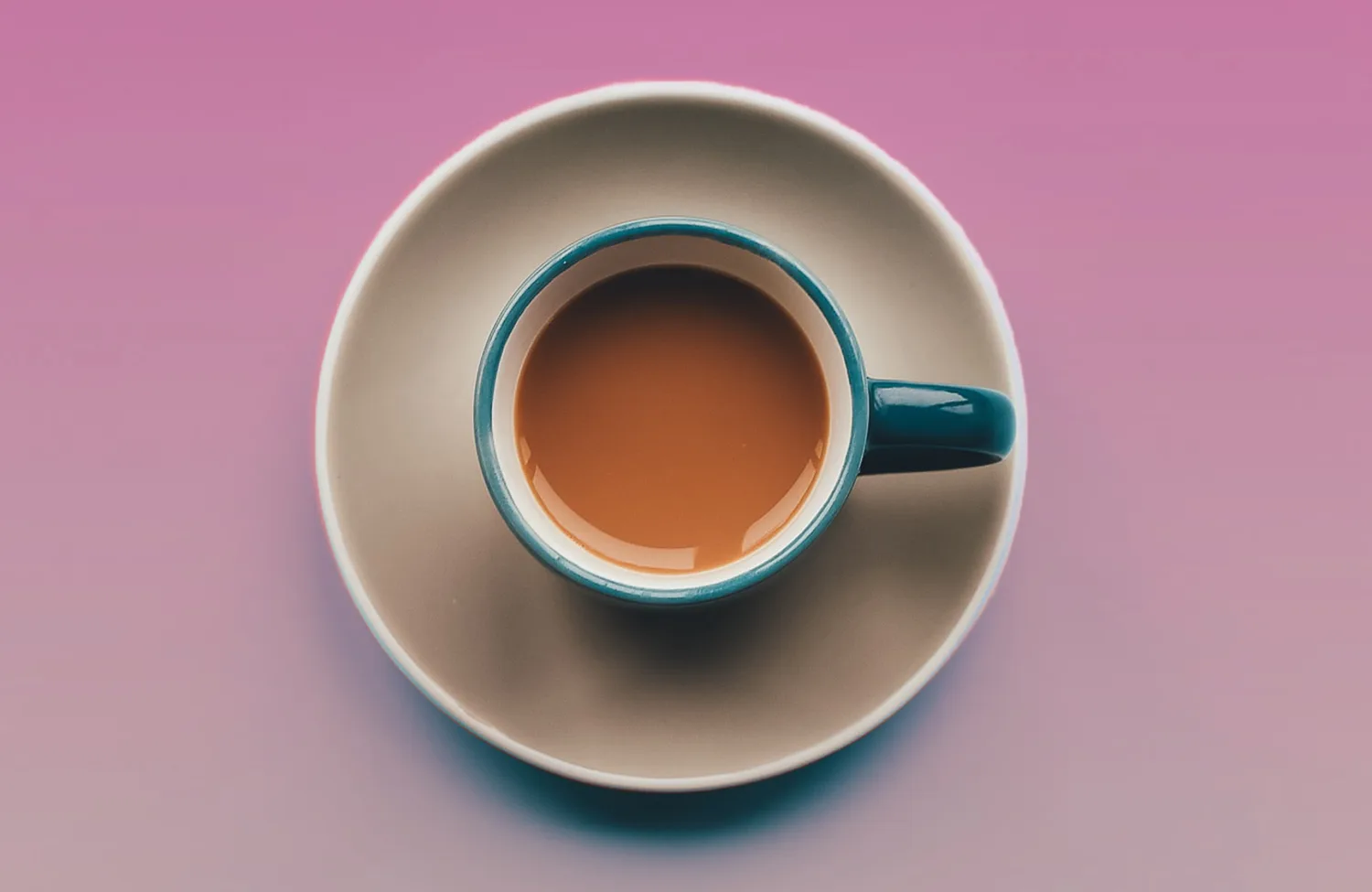 Birds eye view of a saucer and cup with a cold brown coffee in it.