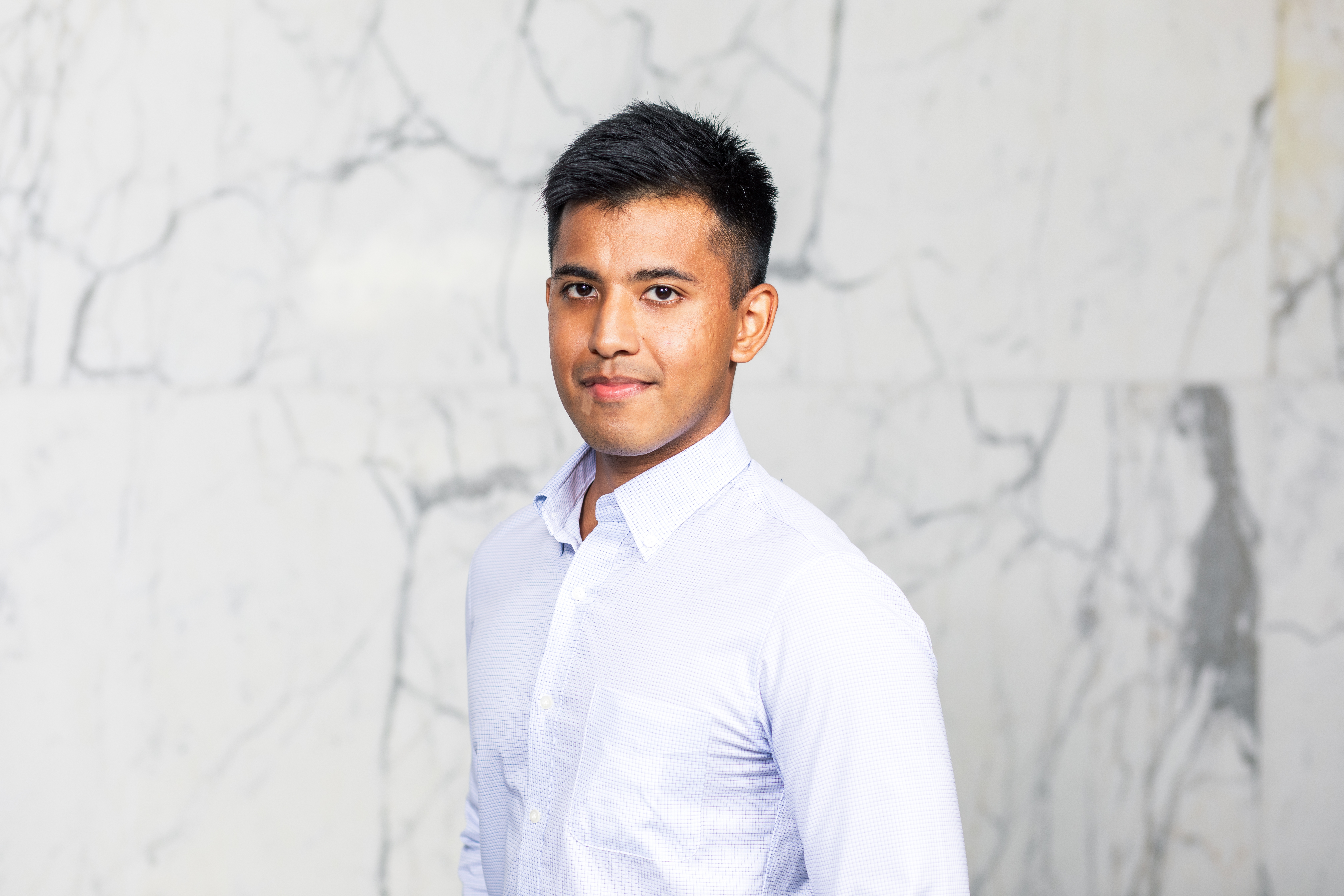 head and shoulders image of Gerald wearing a white shirt in front of a marble wall