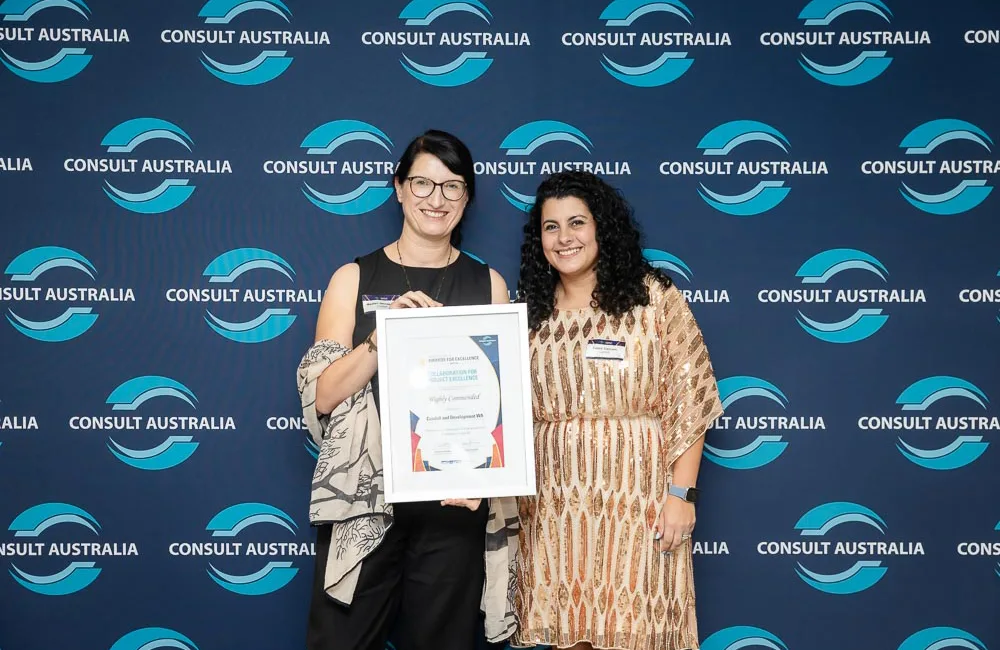 Cundall team holding the framed certificate in front of an award branded wall