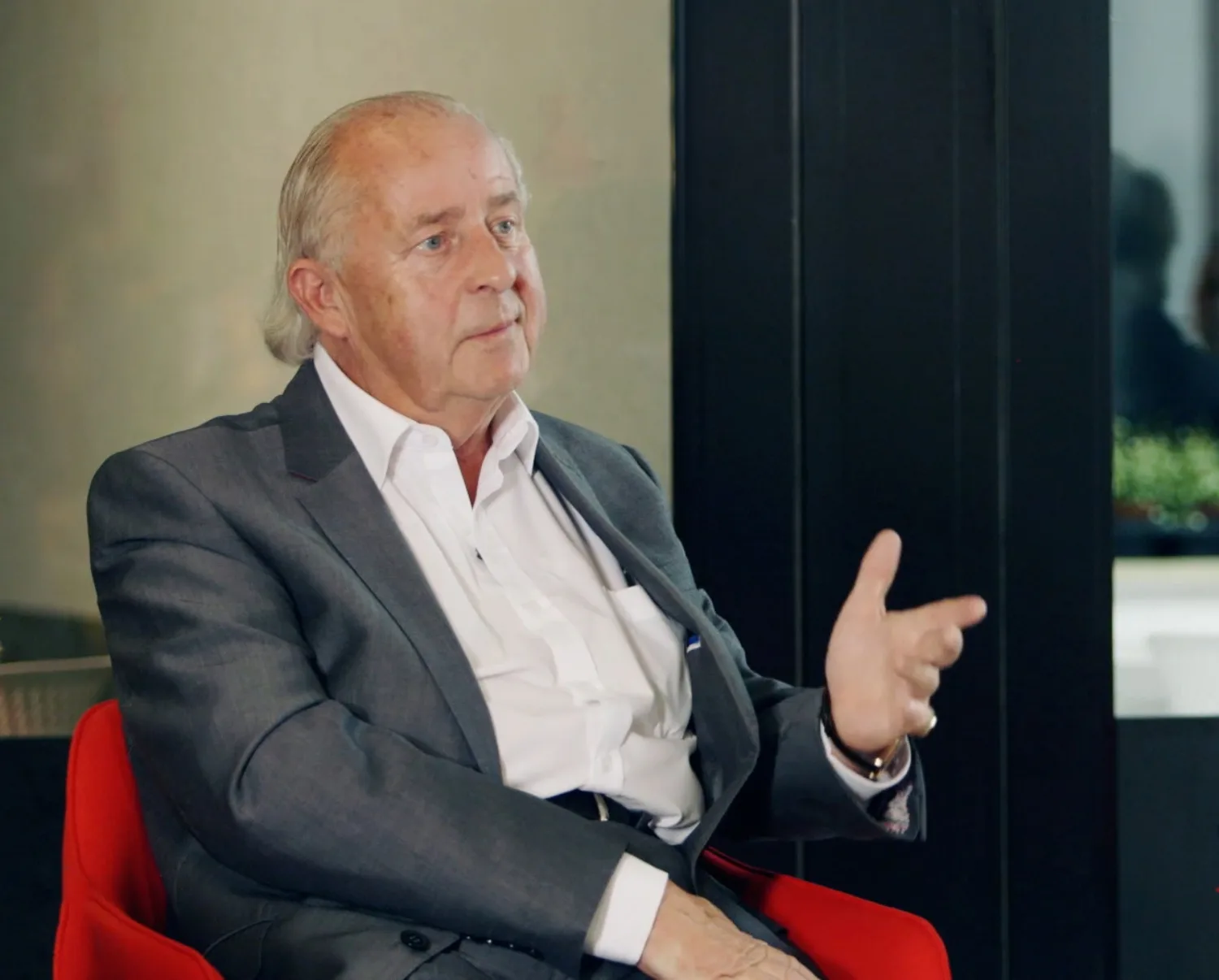 Rick Carr sat in a red chair talking with hands raised
