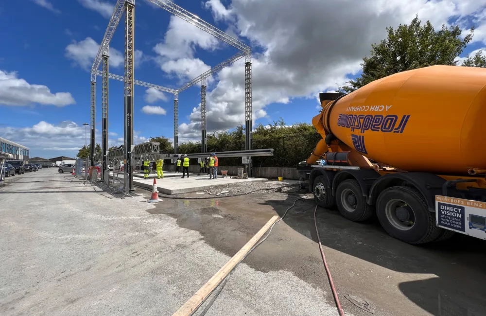 Building site with workers in high vis jackets and large, orange concrete mixer