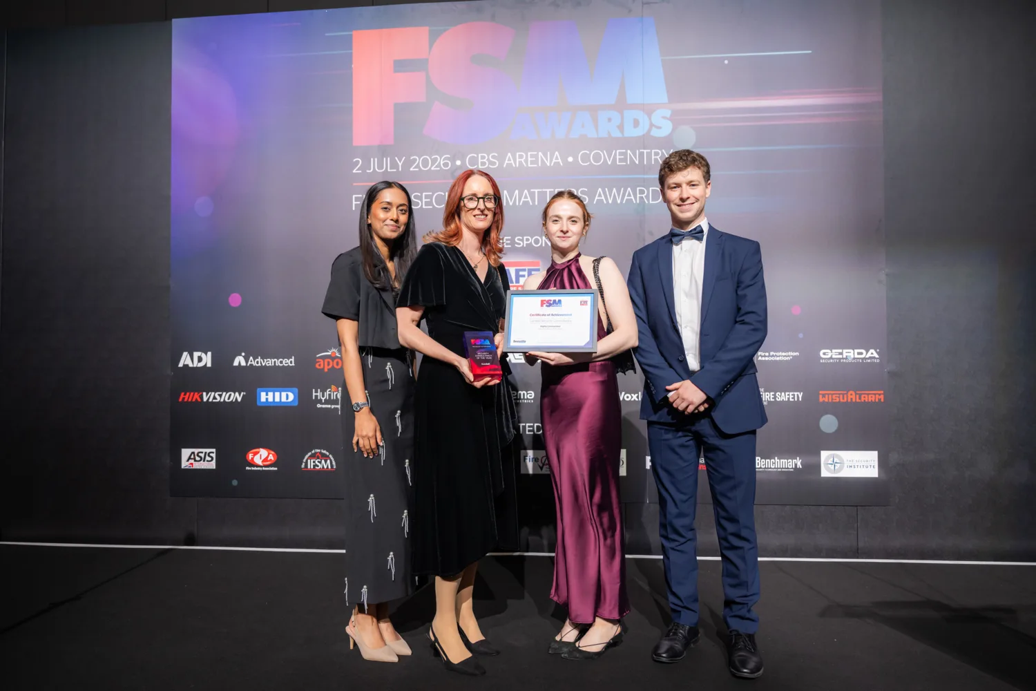 Four people stand on a stage holding a framed certificate and trophy in front of a backdrop reading “FSM Awards, 2 July 2026, CBS Arena, Coventry,” with sponsor logos displayed across the background.