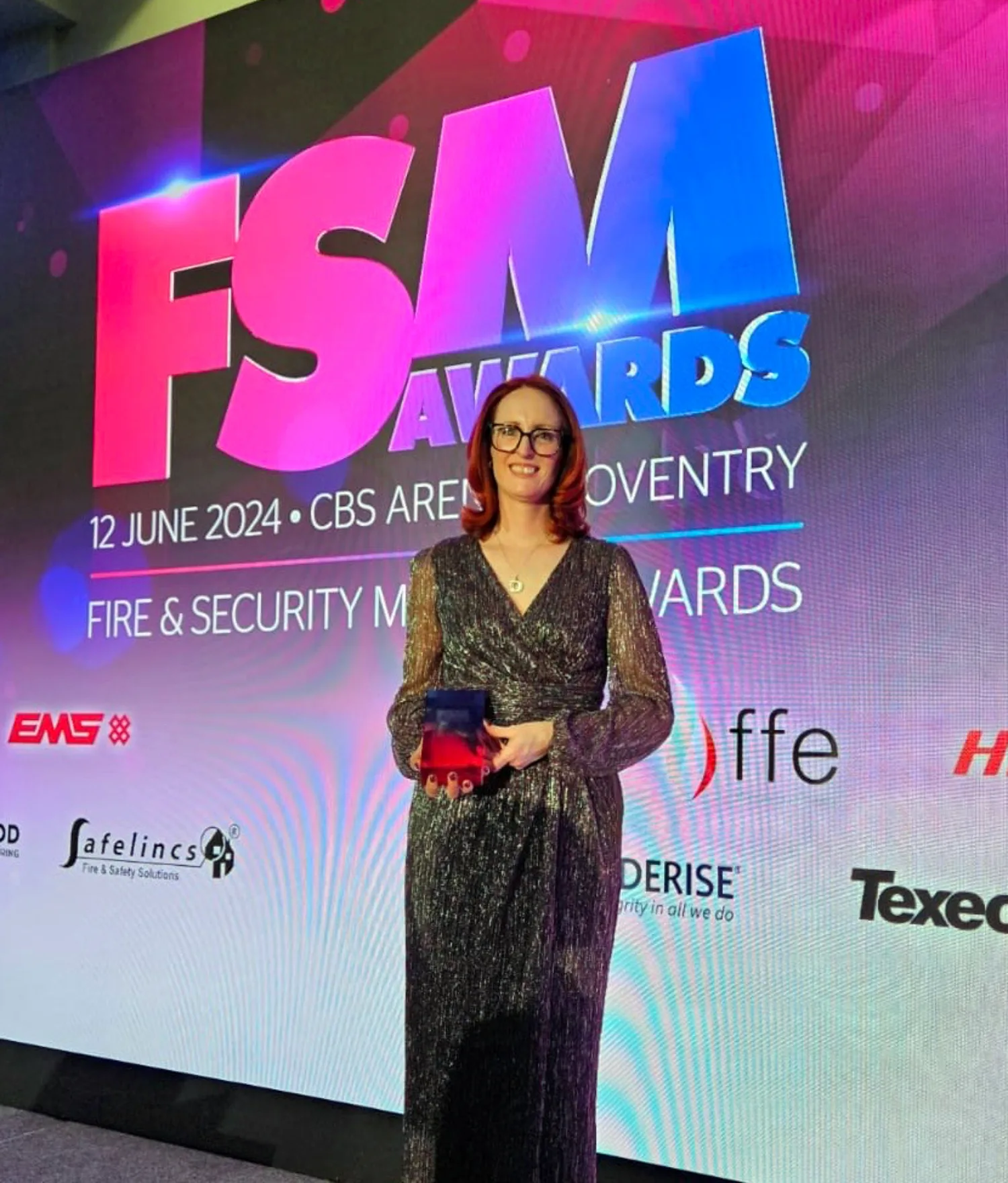 Leigh holding the award in front of the FSM awards screen