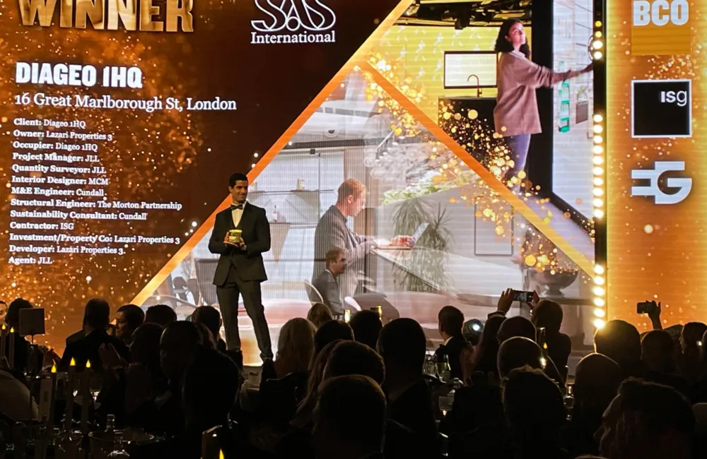 Awards presenter on stage in front of the WINNER Diageo 1 HQ screen