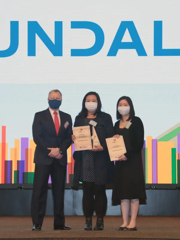 Cundall accepting the award on stage in front of a colourful backdrop and large Cundall logo
