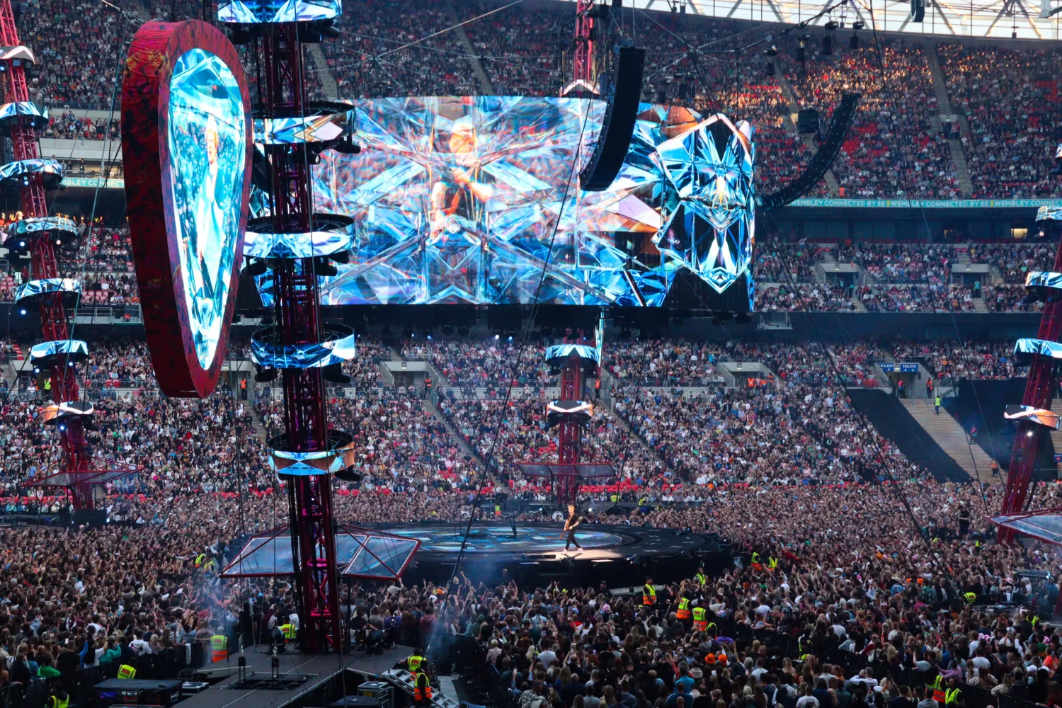 Cable structure above the stage with performer on stage in front of a full stadium