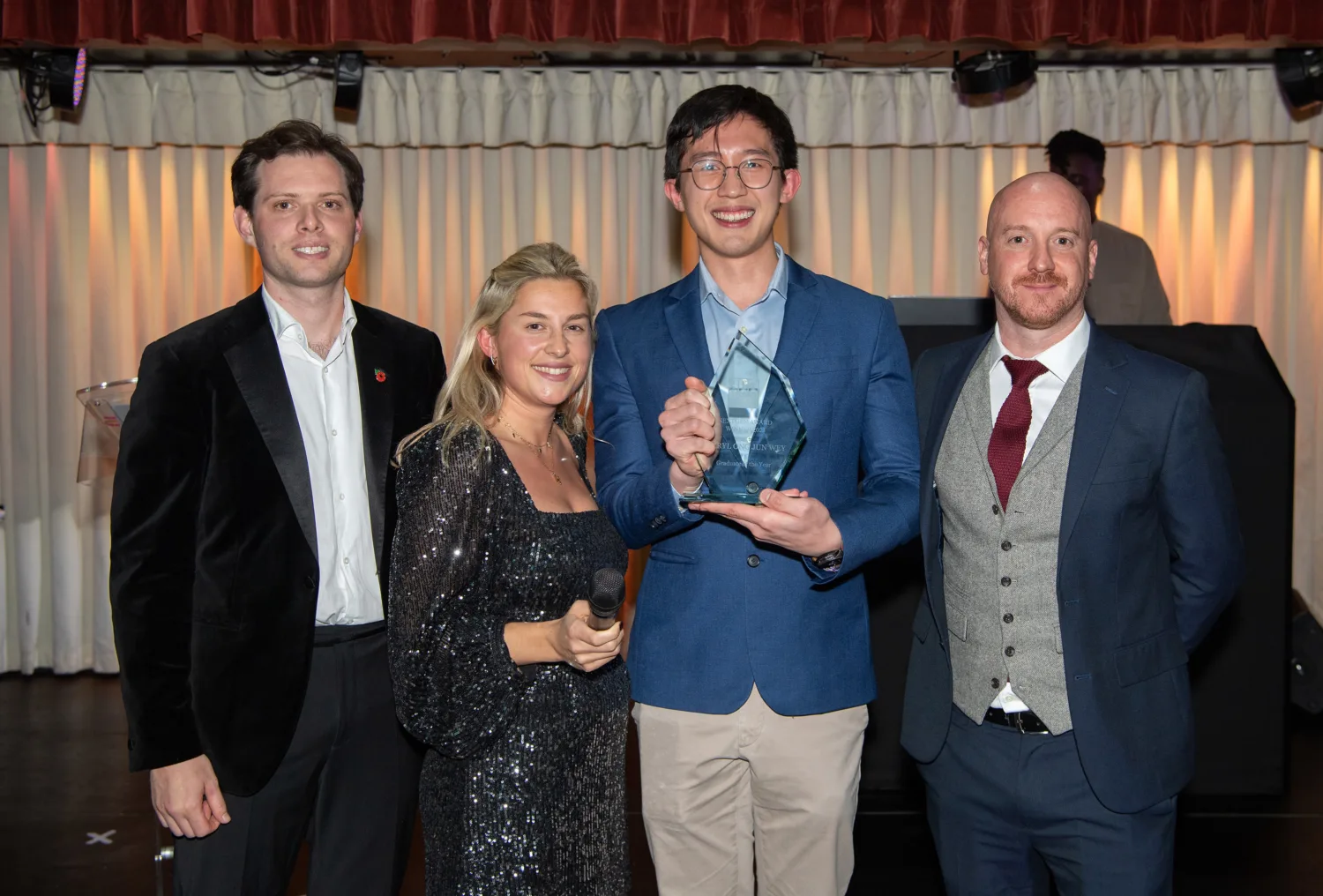Jerryl standing in between judges holding his award