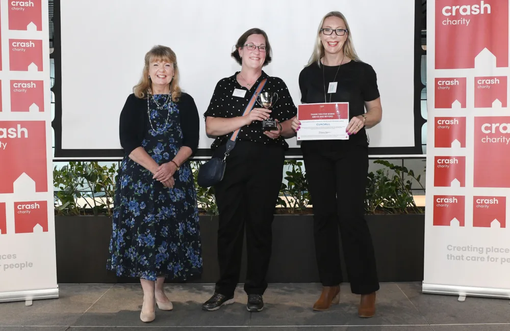 Natasha and Carol on stage recieving the crash award holding up the certificate and the trophy