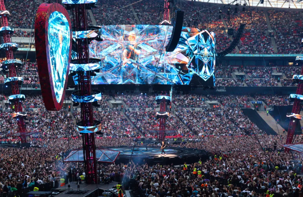 Cable structure above the stage with performer on stage in front of a full stadium