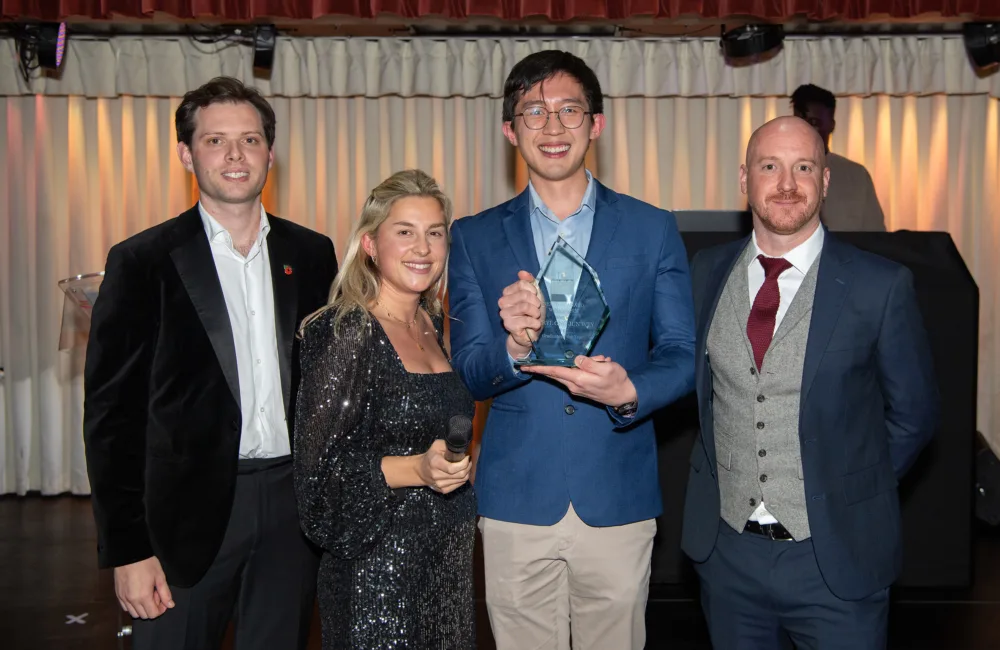 Jerryl standing in between judges holding his award