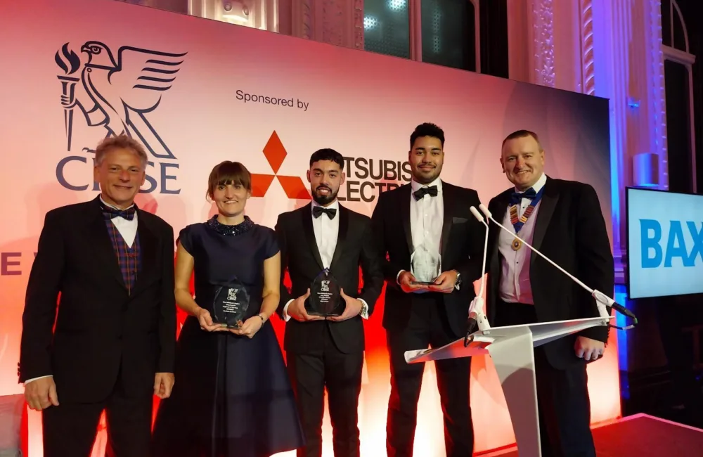 A group of five people standing in a line, the three in the middle are holding CIBSE West Midlands awards
