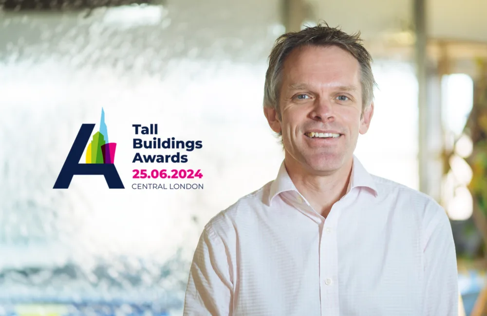 Headshot of Alex smiling with the Tall Building Awards logo on the left.
