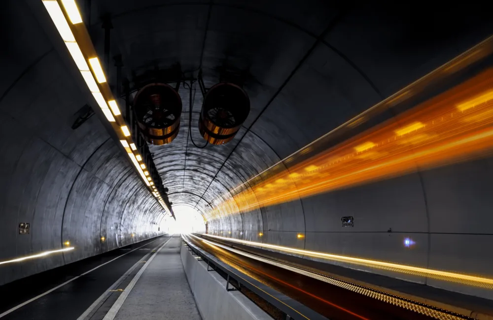 Dark road tunnel with ventilation and bright orange light trails